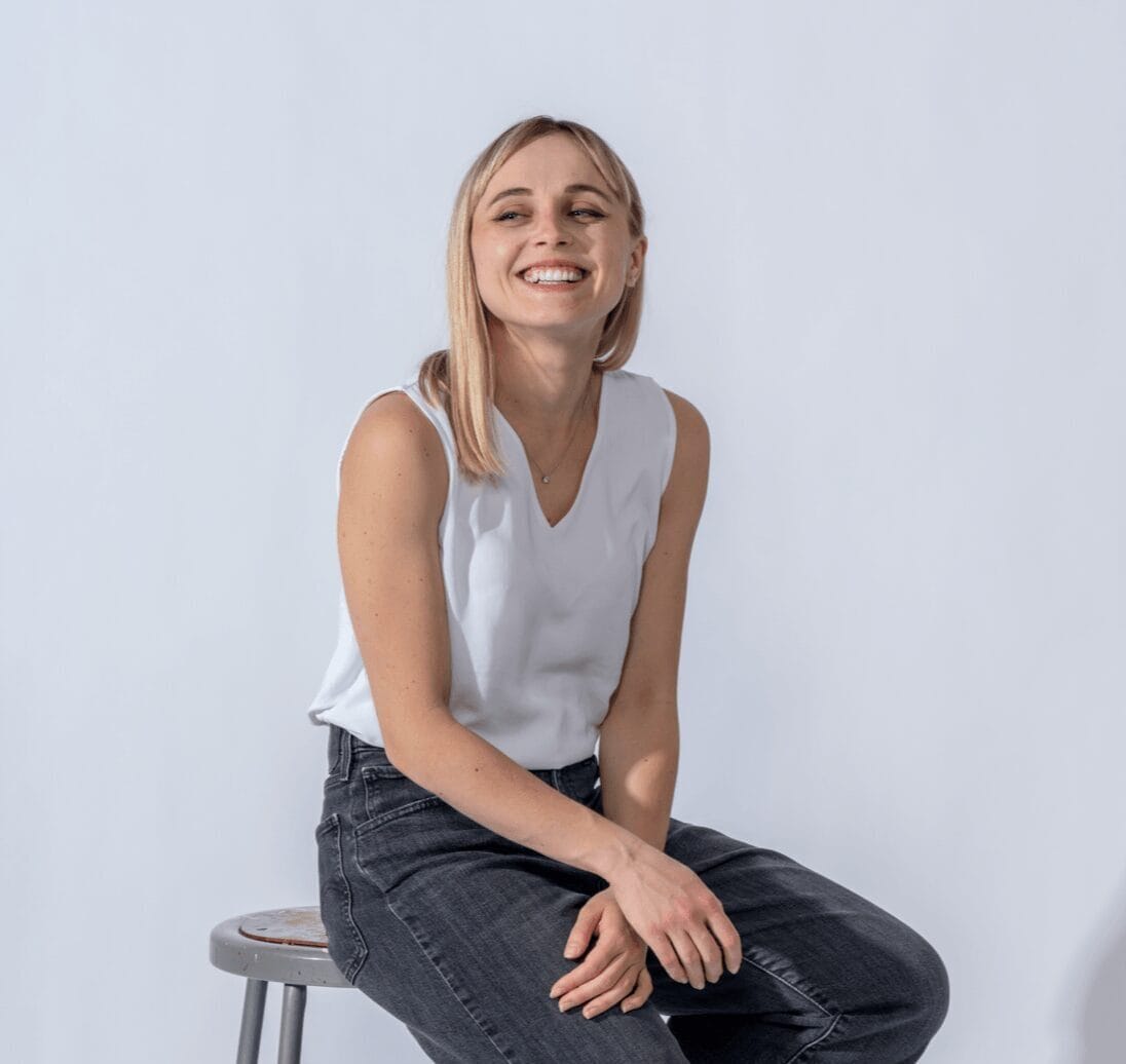 Woman sitting on stool against white background