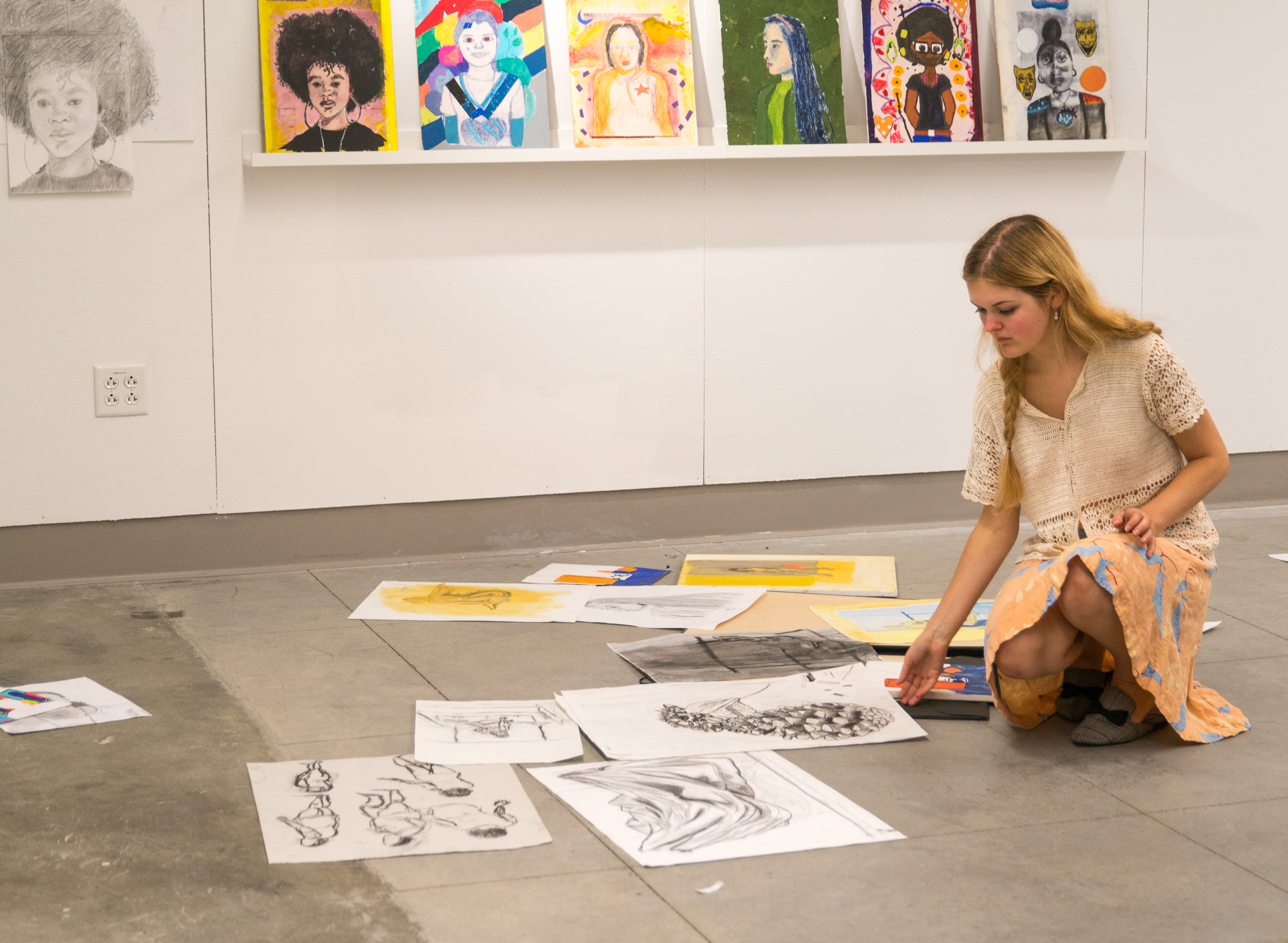 Student looking through artwork on the floor
