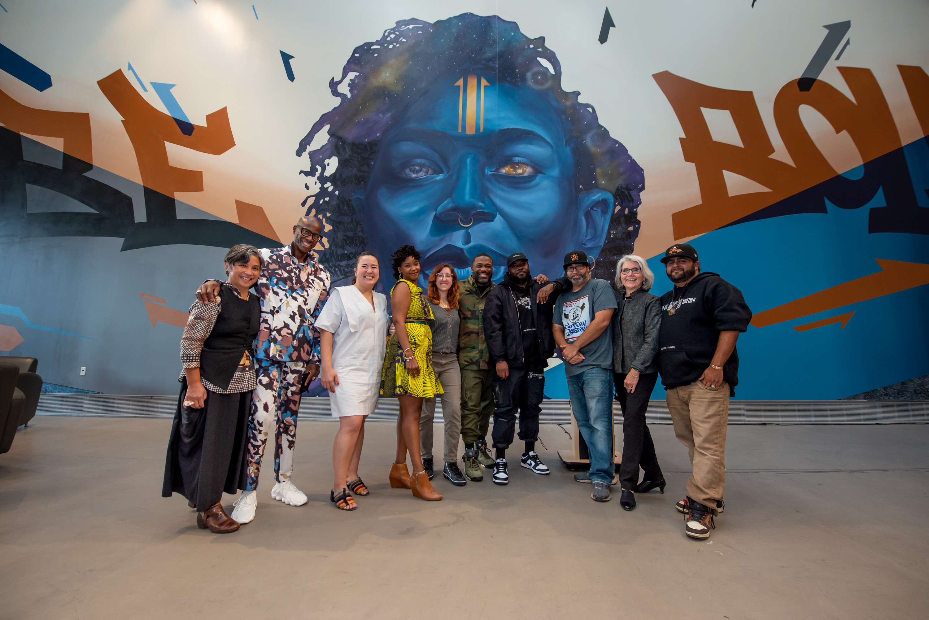 GN Crew standing with MassArt President Mary Grant and college administrators in front of the new mural in the DMC