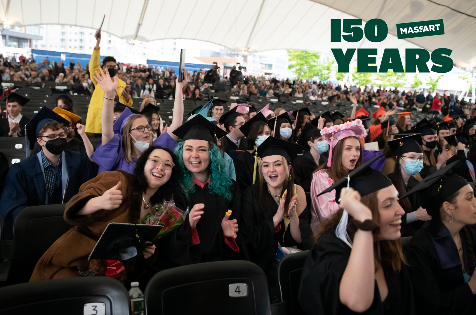 MassArt Commencement, 2022, Leader Bank Pavilion, © Melissa Ostrow Students smiling and cheering at MassArt Commencement, 2022, Leader Bank Pavilion